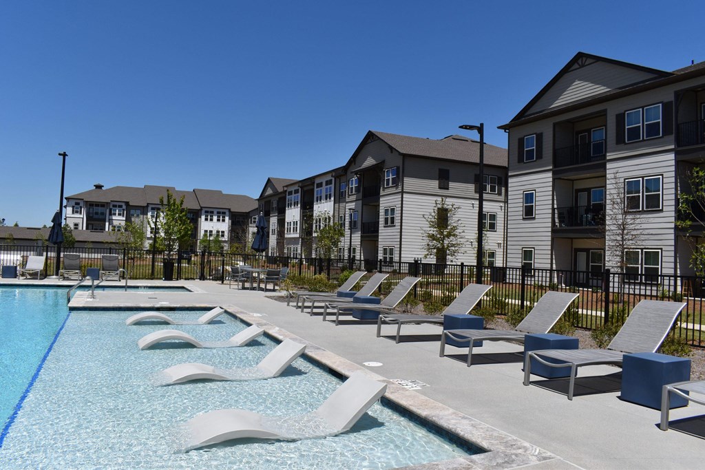 a swimming pool with lounge chairs in front of apartment buildings at Century Mundy Mill Apartments, Oakwood