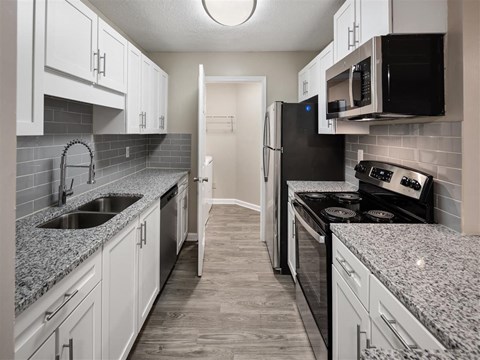 a kitchen with granite counter tops and white cabinets
