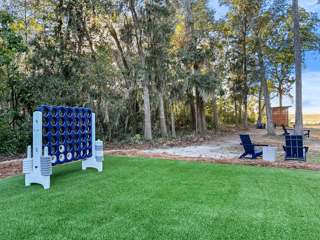 A blue cornhole game set up in a grassy area with trees in the background.