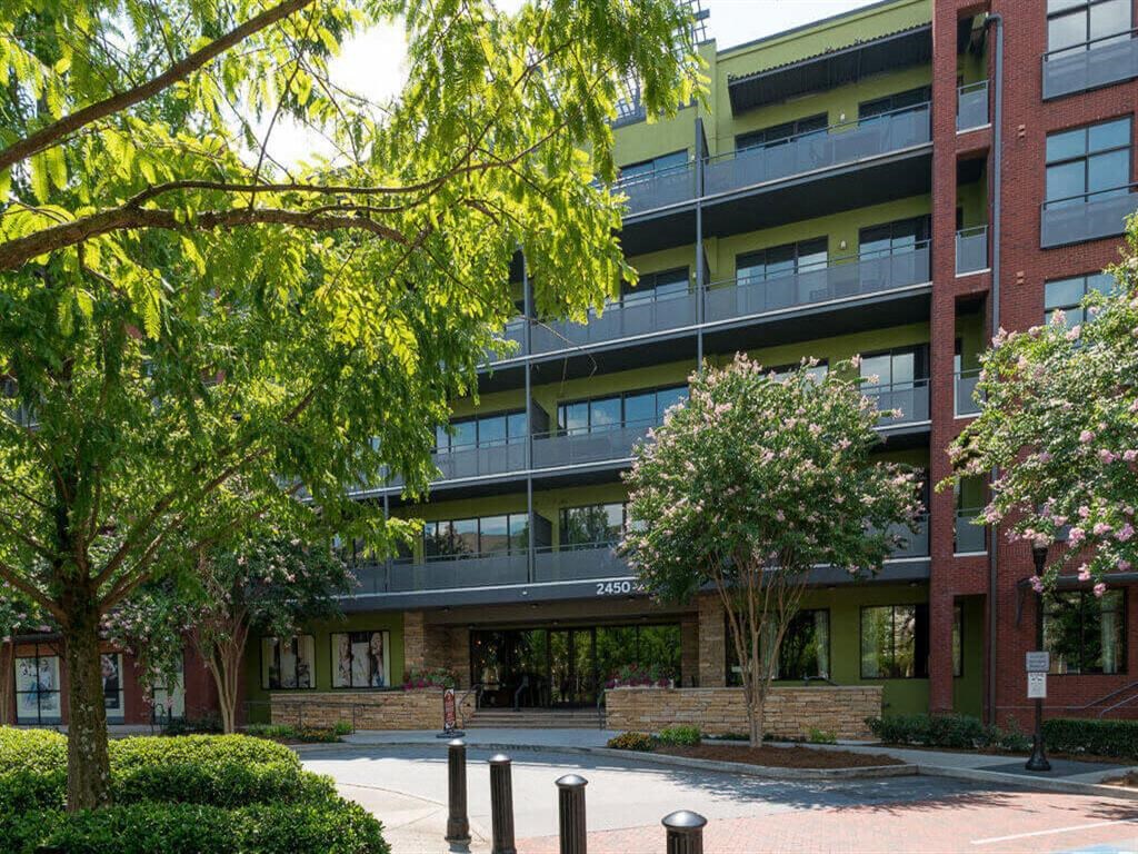 an apartment building with a courtyard and trees in front of it