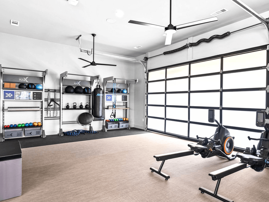 A gym with a rowing machine in the foreground and racks of equipment in the background.