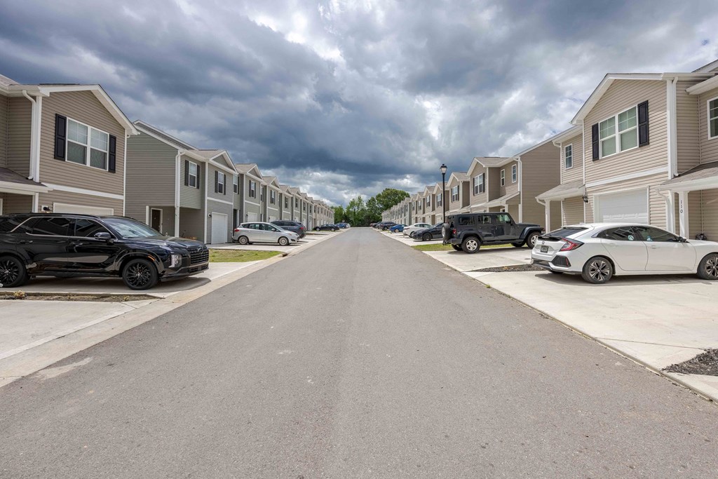 a street with houses on both sides of it and cars parked on the curb