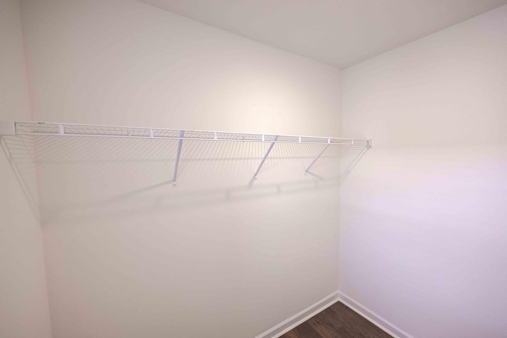 a closet with a white wall and a hanging rack on the wall