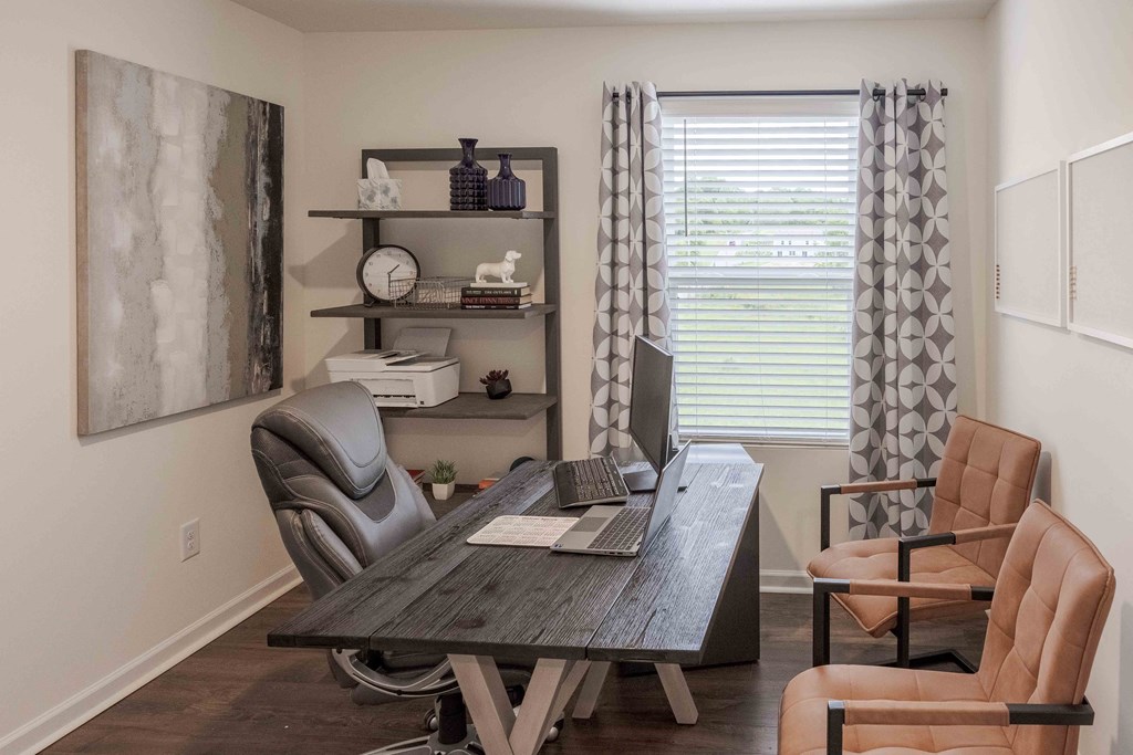 a home office with a desk and chairs and a window