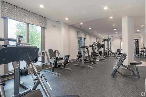 A spacious gym with a variety of equipment and a large window.