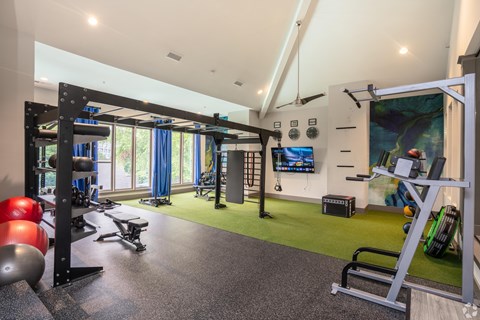 A gym with a variety of equipment including a weight bench, a pull up bar, and a treadmill.