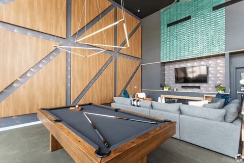 A pool table is in the middle of a room with a couch and a television.