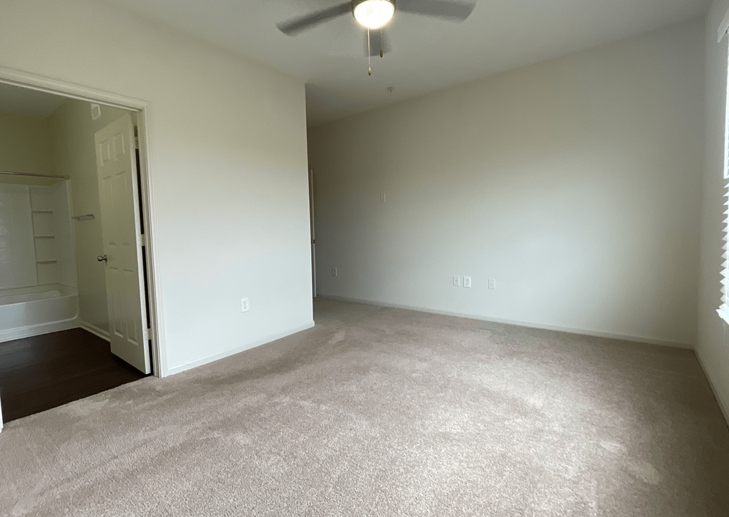 an empty living room with white walls and a ceiling fan