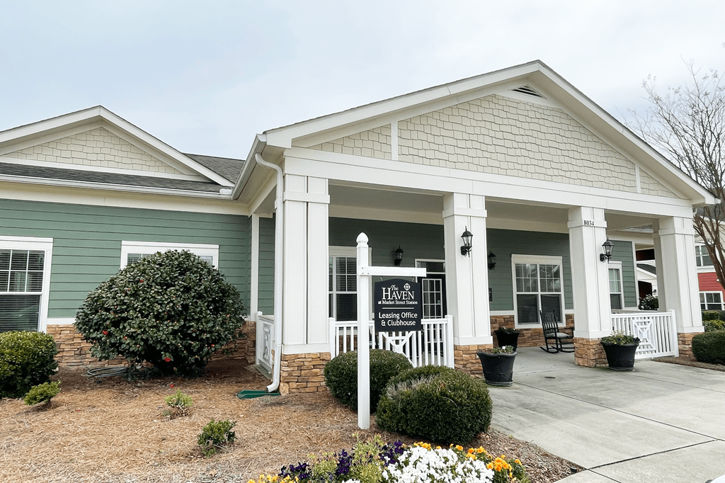 a house with a porch and a sign in front of it