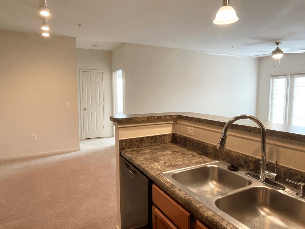 an empty kitchen with granite counter tops and a sink