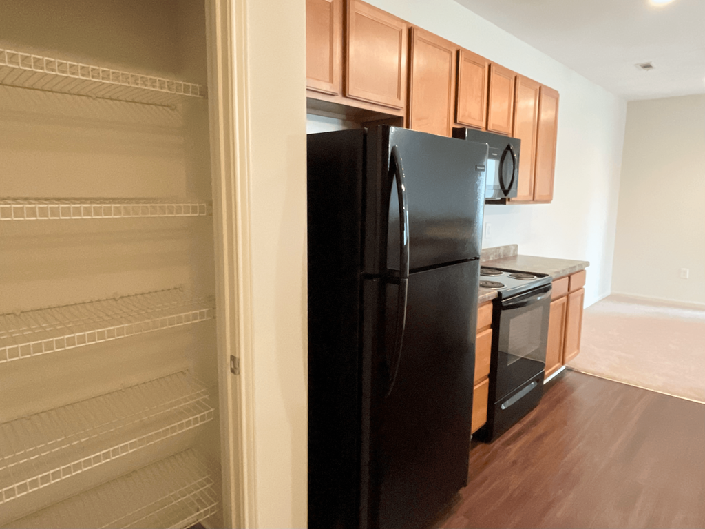 a kitchen with a black refrigerator and wooden cabinets