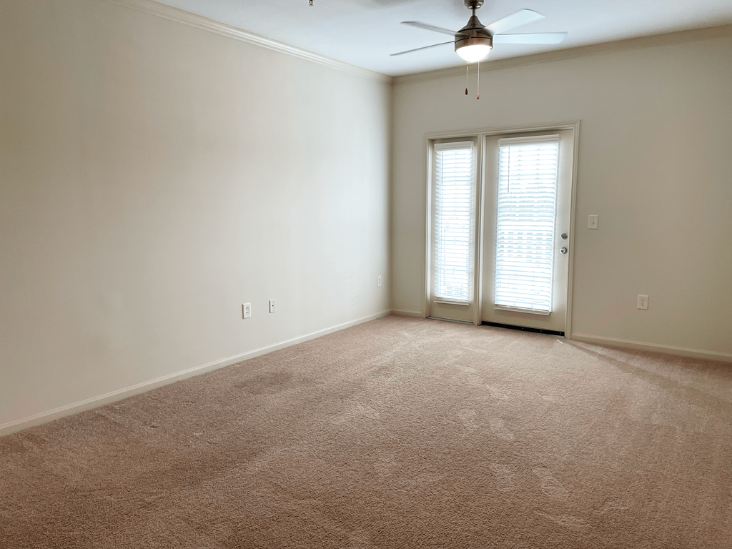 an empty living room with white walls and a ceiling fan