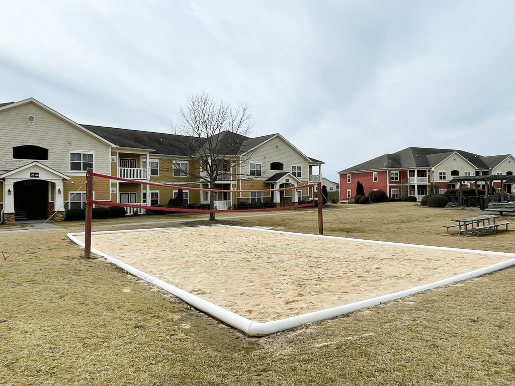 a sand volleyball court in front of a row of houses