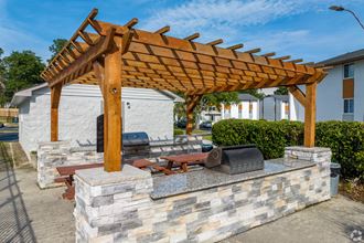 a wooden pergola with a stone wall around it and a stone grill with a grill - Photo Gallery