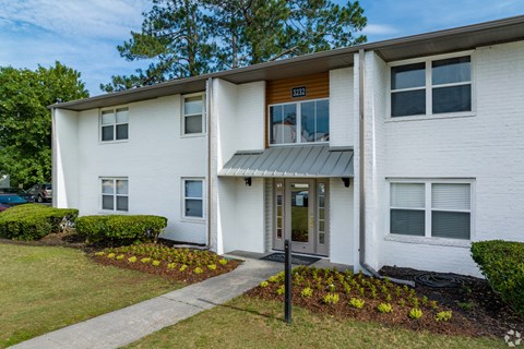 a white building with a gray awning and a green lawn at Summit Augusta, Augusta, GA 30909