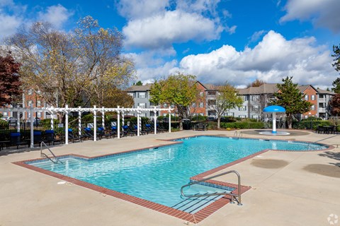 A large swimming pool surrounded by a white fence and trees.