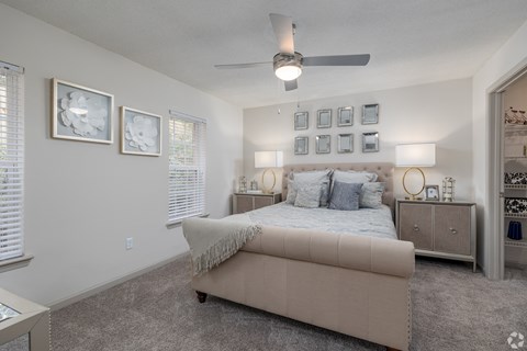 A bedroom with a bed, nightstands, and pictures on the wall.