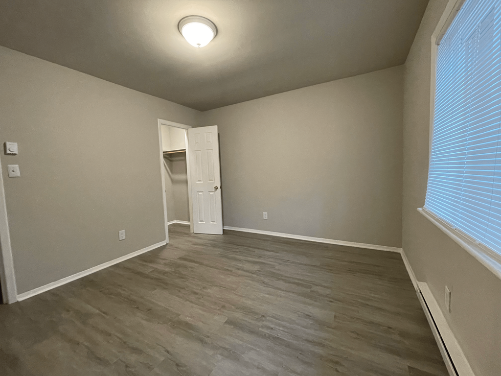 an empty living room with a large window and wood flooring