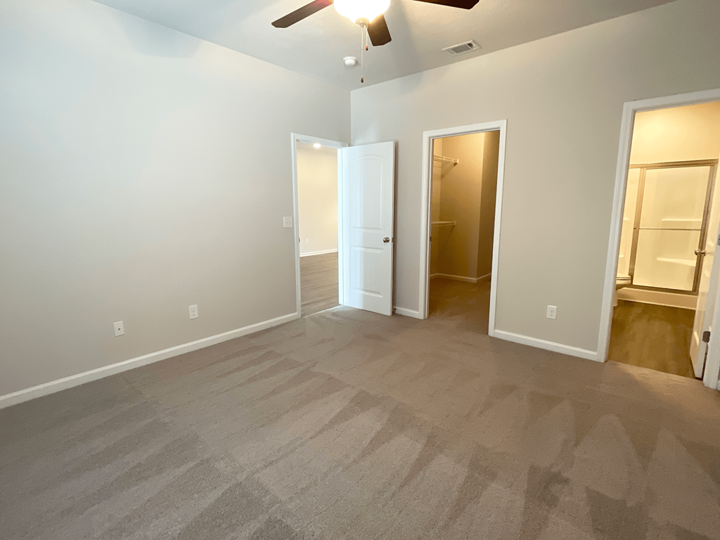 an empty living room with carpet and a ceiling fan