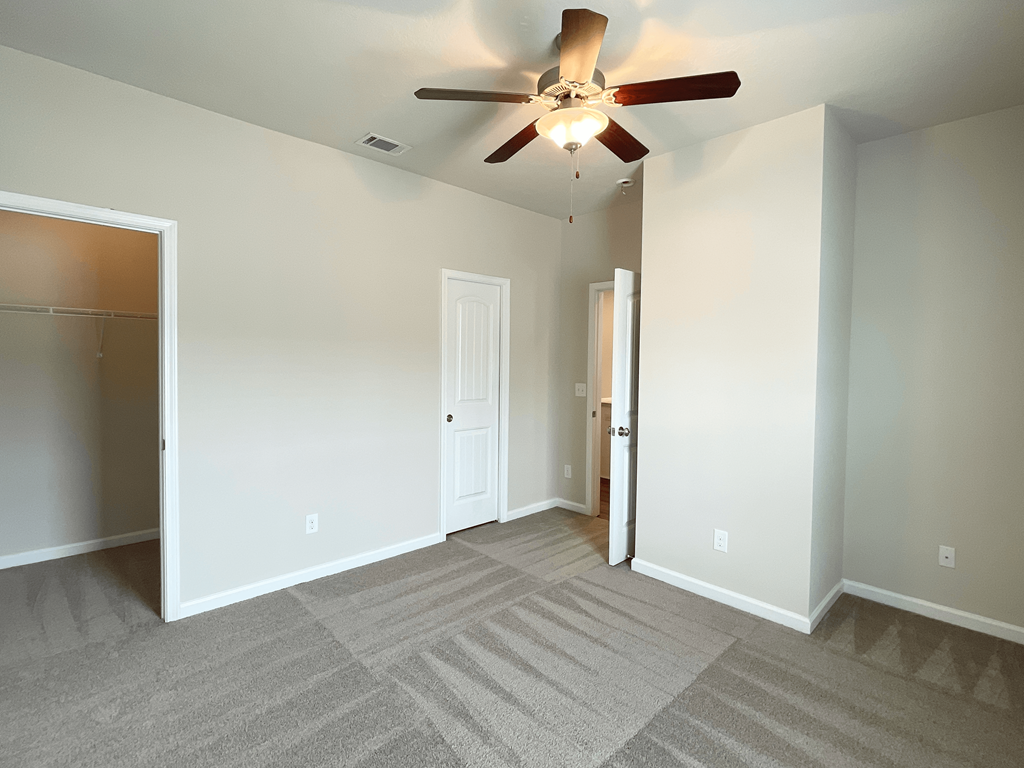 an empty living room with a ceiling fan