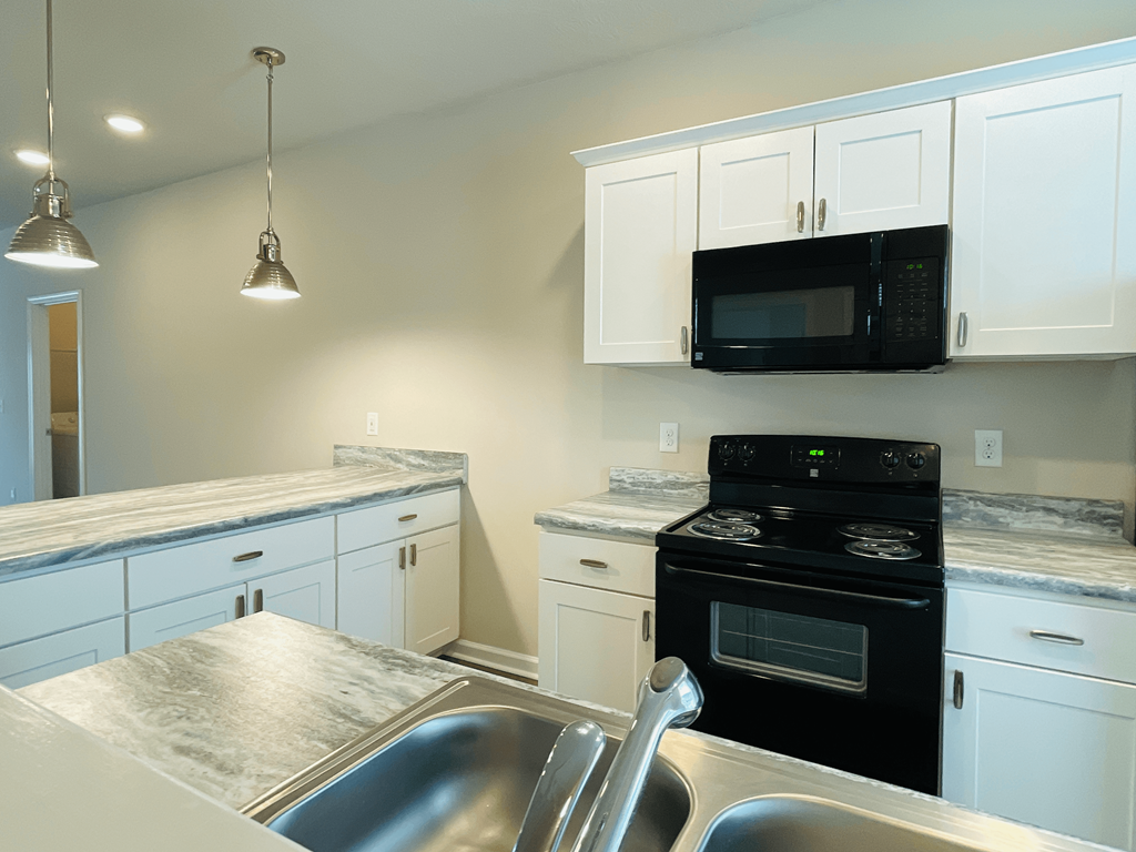 a kitchen with white cabinets and black appliances and a sink