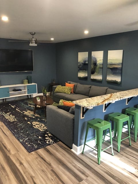 a living room with a couch and a bar with green stools