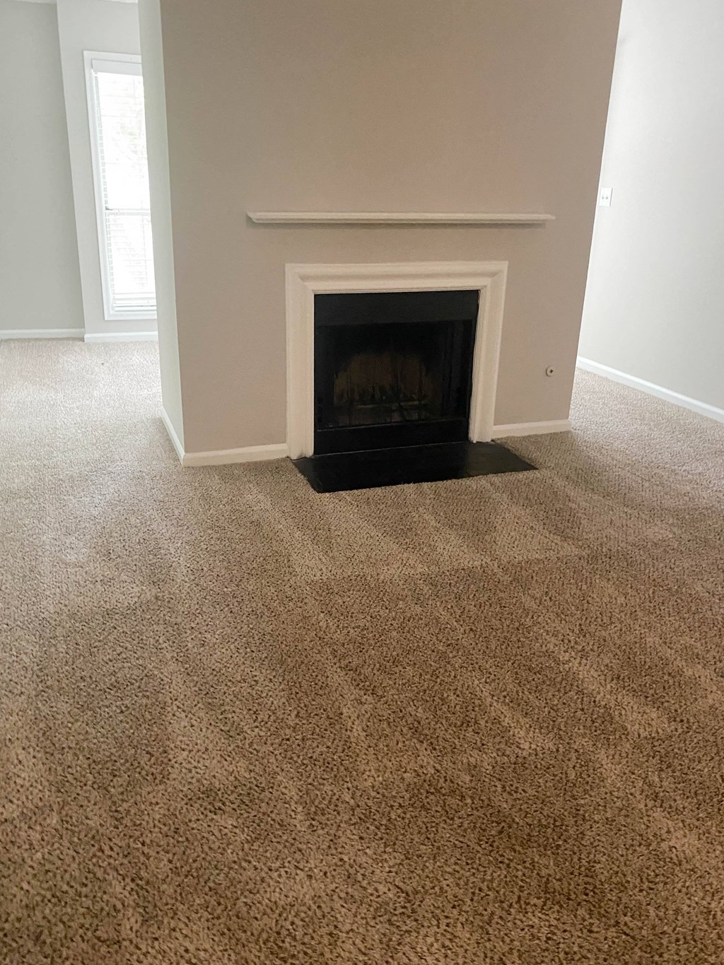 a carpeted living room with a fireplace