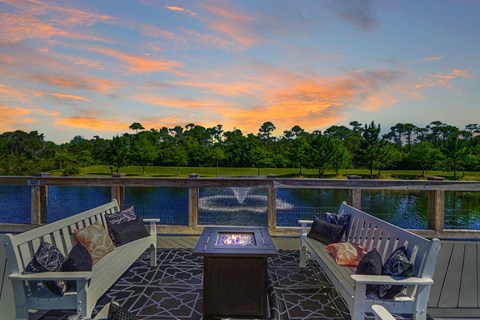 a patio with two chairs and a table on a deck overlooking a body of water