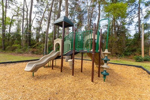 A playground with a green slide and a brown slide.