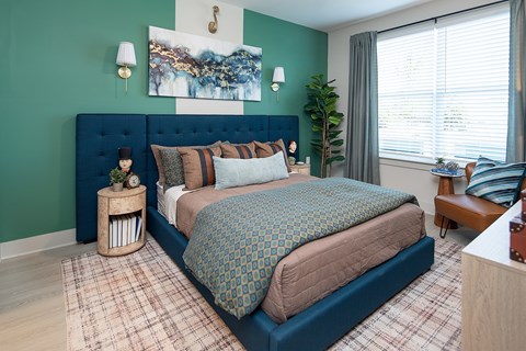 A bedroom with a blue headboard and a large bed with a patterned comforter.