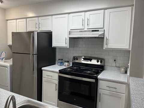 a kitchen with white cabinets and stainless steel appliances