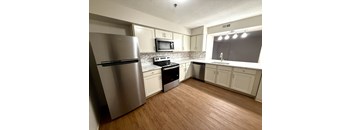 A kitchen with a stainless steel refrigerator and wooden floors.