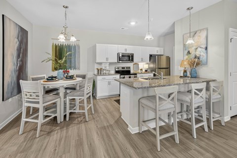 A kitchen with a table and chairs in front of it.