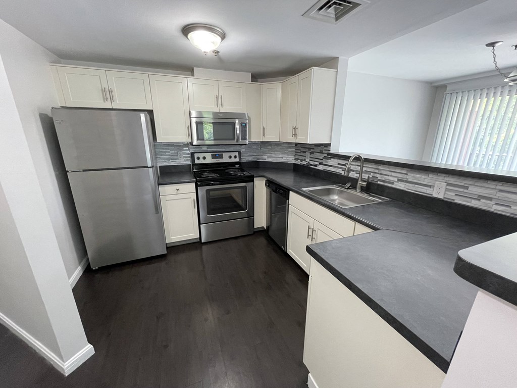 A kitchen with a stainless steel refrigerator, microwave, oven, and sink.