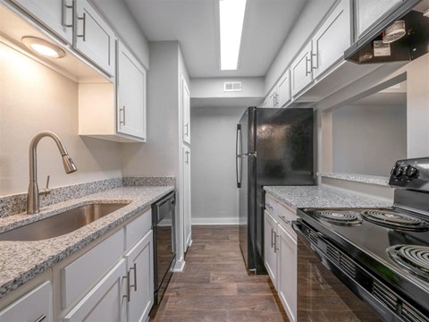 A modern kitchen with a black refrigerator and stove top oven.