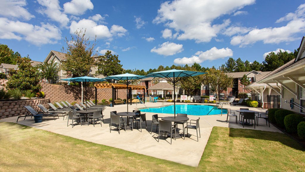 a swimming pool with tables and umbrellas in front of a house at Emery Village, Georgia, 30504