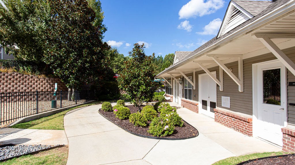 a sidewalk in front of a house with a yard and trees at Indigo Apartments Gainesville, Gainesville Georgia