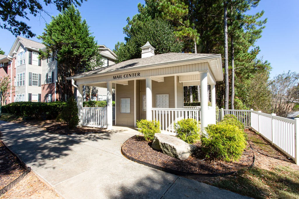 a small white building with a porch and a sidewalk at Indigo Apartments Gainesville, Gainesville