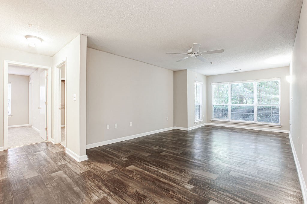 an empty living room with a large window and wooden floors at Indigo Apartments Gainesville, Gainesville, GA