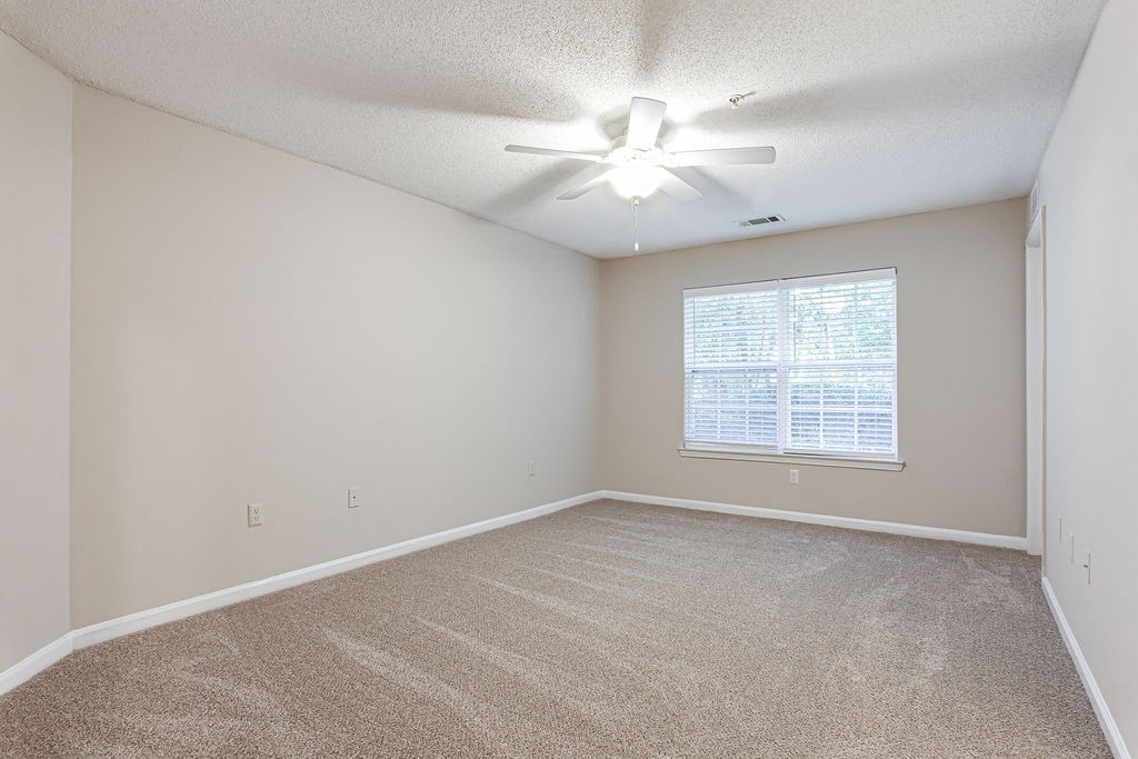 an empty living room with a ceiling fan and a window  at Indigo Apartments Gainesville, Gainesville, 30504