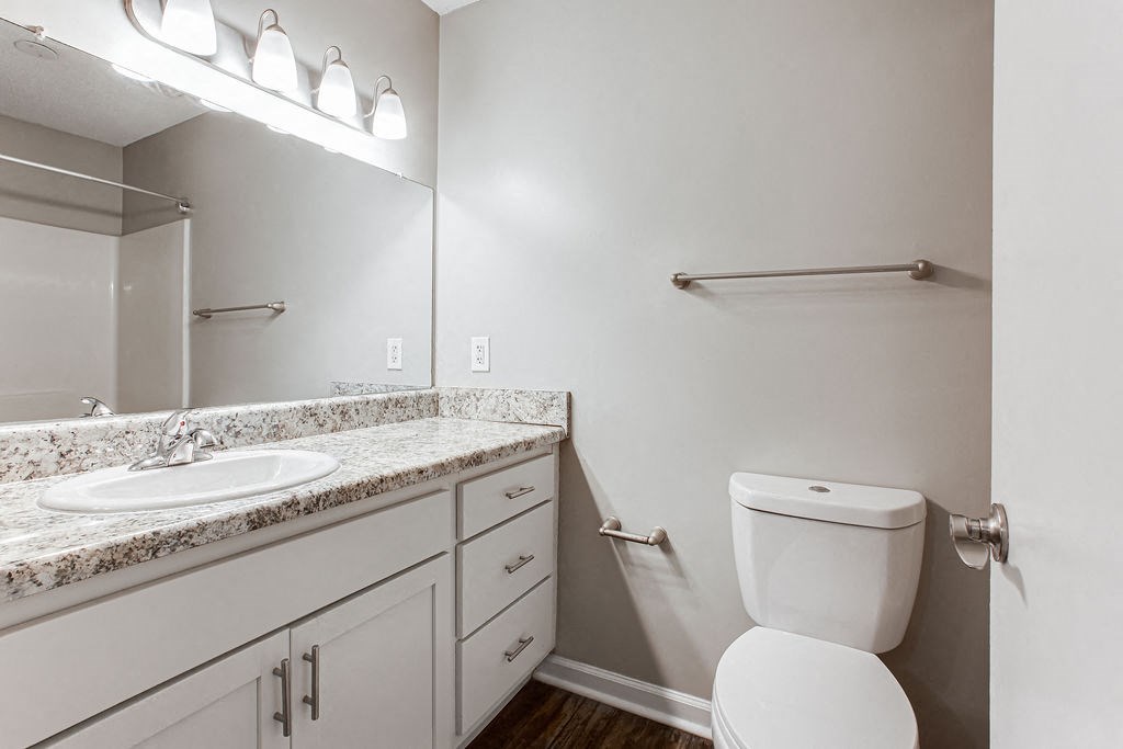a bathroom with a toilet and a sink and a mirror at Indigo Apartments Gainesville, Gainesville, GA 30504
