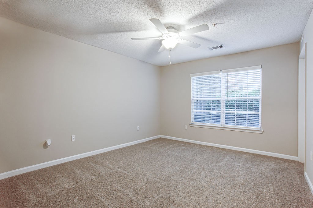 an empty living room with a large window and a ceiling fan at Indigo Apartments Gainesville, Gainesville Georgia