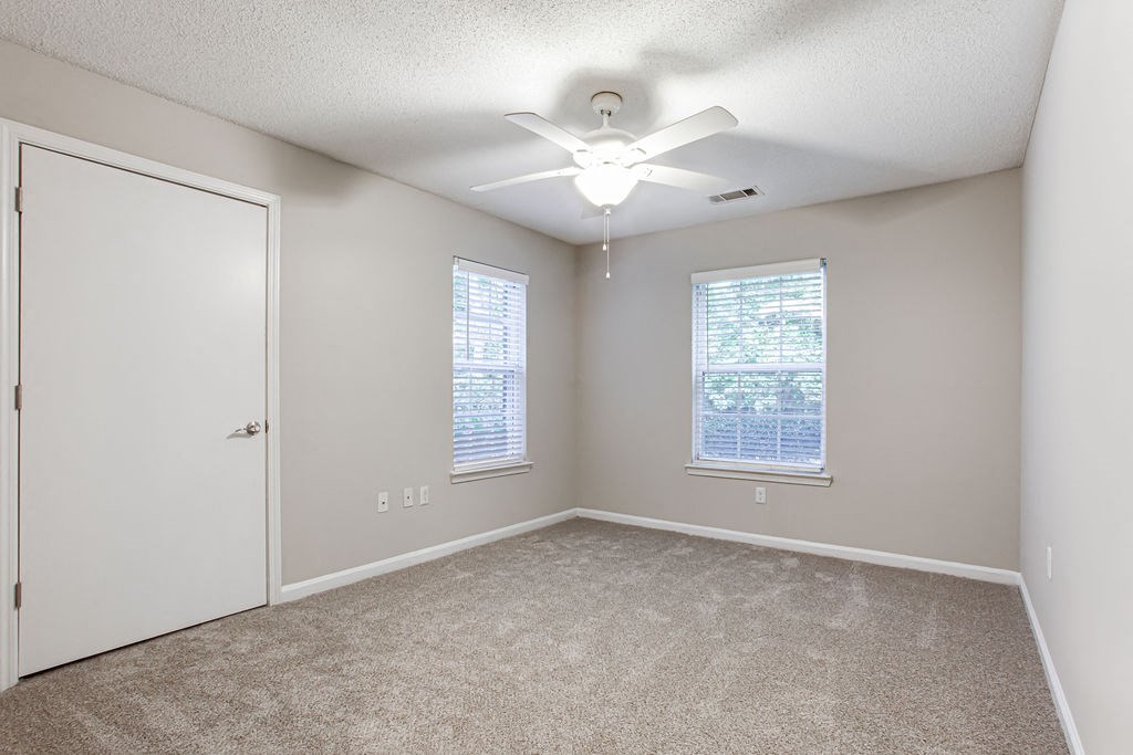 an empty room with a ceiling fan and two windows at Indigo Apartments Gainesville, Gainesville, GA