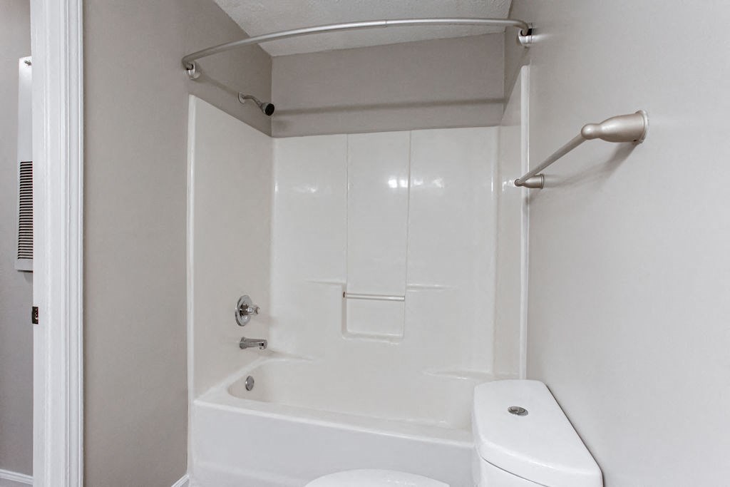 a white bathroom with a white toilet and a bath tub at Indigo Apartments Gainesville, Georgia