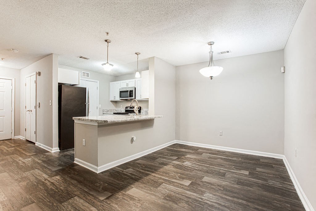 an empty living room and kitchen with a counter top and a refrigerator at Indigo Apartments Gainesville, Gainesville