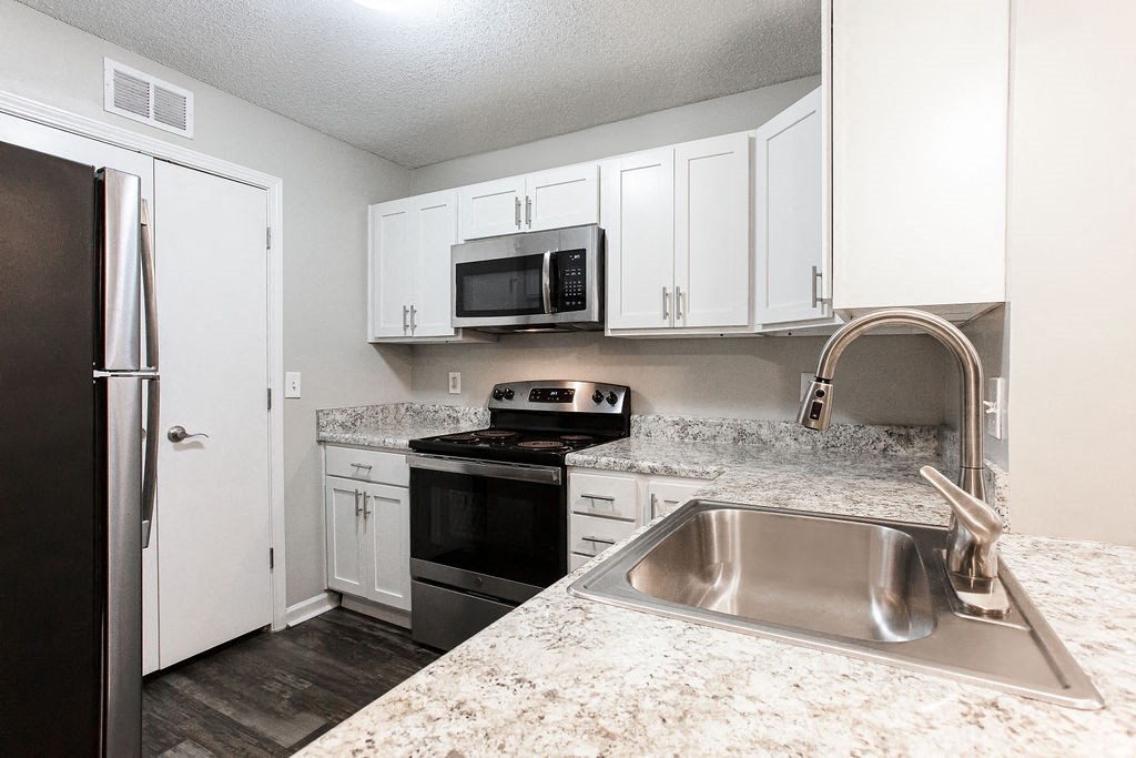 a kitchen with granite counter tops and white cabinets at Indigo Apartments Gainesville, Georgia