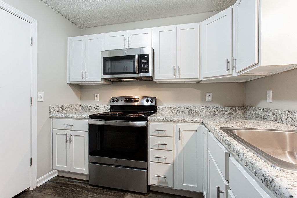 a kitchen with white cabinets and a stove and microwave at Emery Village, Georgia, 30504