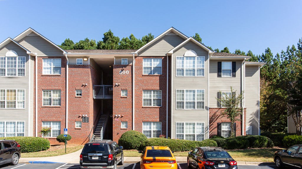 an apartment building with cars parked in front of it at Indigo Apartments Gainesville, Gainesville