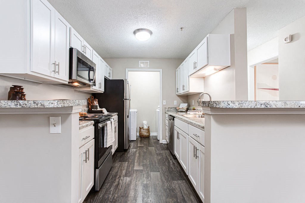 a kitchen with white cabinets and black appliances at Indigo Apartments Gainesville, Gainesville Georgia