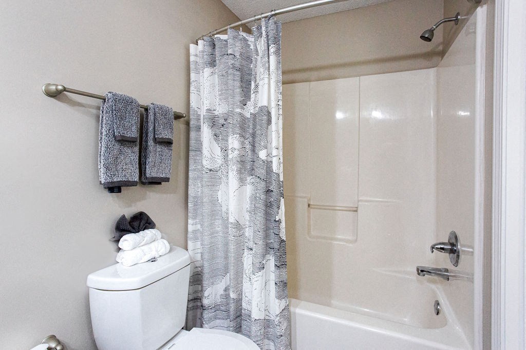 a bathroom with a shower and a toilet and a shower curtain at Indigo Apartments Gainesville, Gainesville